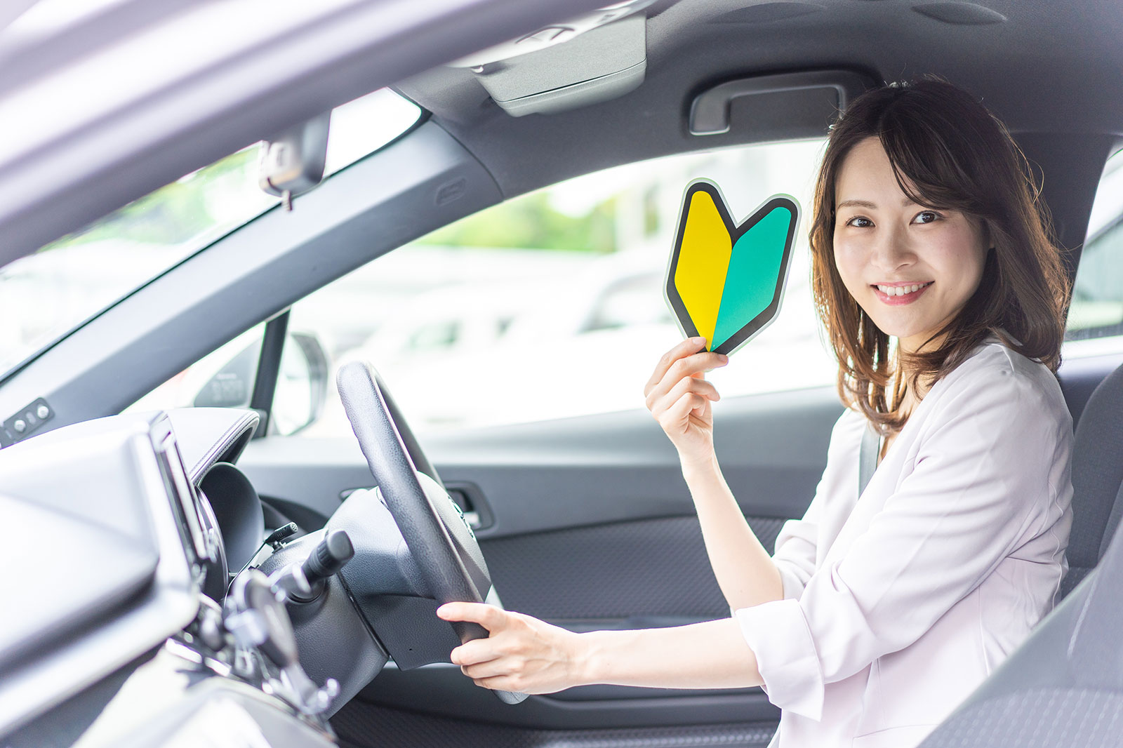 笑顔で初心者マークを持つ女性